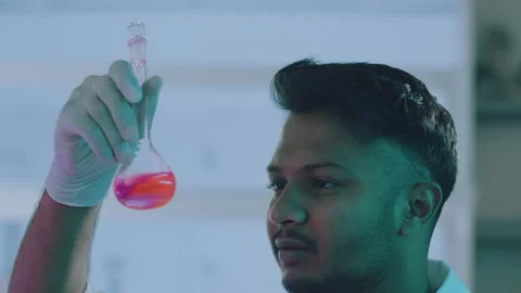 Close Up of an Ethnic Handsome Lab Worker Examining and Holding a Lab Flask Stock Footage 164991817