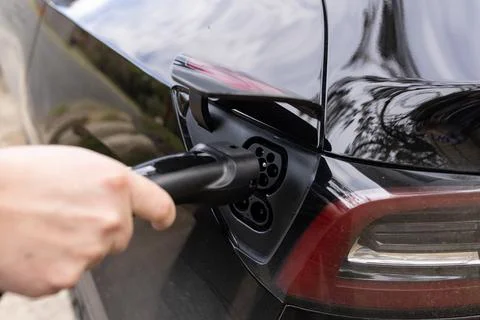 A close up of a EV charger plug being plugged into an electric vehicle car Stock Photos