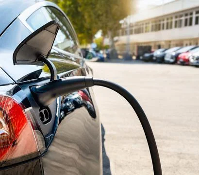 Close-up of EV charging plug inserted into electric car at charging station.  Stock Photos