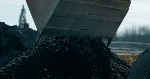 Close-up of excavator bucket digging into pile of dark soil at construction site Stockbeeldmateriaal 329562610