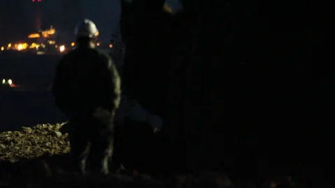 Close up of an excavator operating at night with a power plant in the backgr 스톡 동영상 121405131