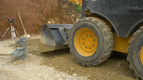 CLOSE UP: Excavator operator uses the front bucket to level a layer wet gravel Stock Footage 137537690