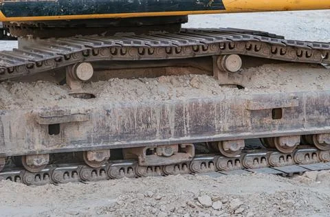 Close-up of an excavator underside, showcasing metal tracks and rollers, in a Foto stock
