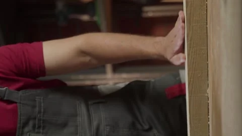Close-up of an experienced carpenter, a man runs his hand over the wood that he 스톡 동영상 281673623