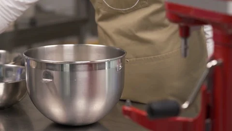 A close-up of an expert baker adding flour to a metallic mixer bowl in the Stock Footage 106247353
