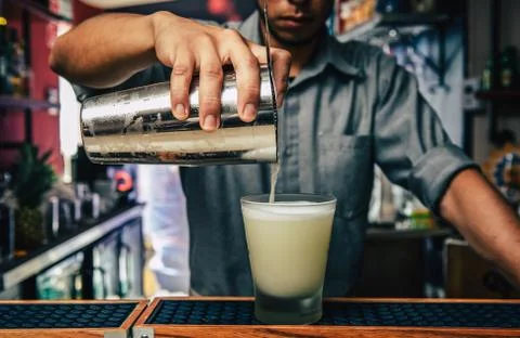 Close-up of expert bartender making Pisco Sour white cocktail with dried lime Foto stock