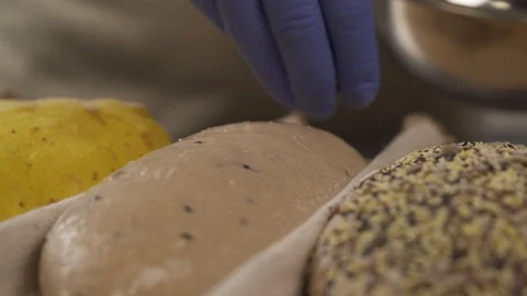 A close-up of an expert chef decorating loafs of bread before baking. Bakery Stock Footage 106379048