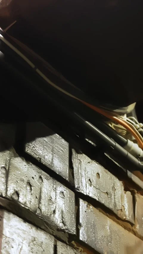 Close-up of exposed electric wires and utility conduits fixed along a rough Stockbeeldmateriaal 333655422