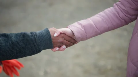 Close-up of extended hand in pink winter jacket reaching towards another hand Video stock 318629615
