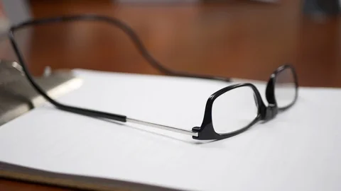 Close-up of eye glasses sitting on a note pad in an office or boardroom. Stock Footage 99999118