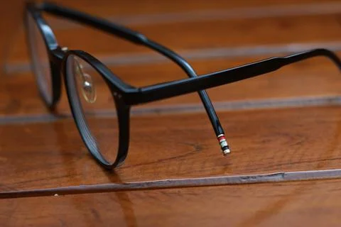 A close up of eyeglasses with black frames isolated natural patterned woode.. Stock Photos