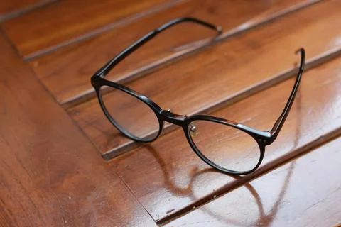 A close up of eyeglasses with black frames isolated natural patterned woode.. Stock Photos