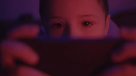 Close up eyes face small boy looks at a smartphone before going to bed in a dark Stock Footage 127168639
