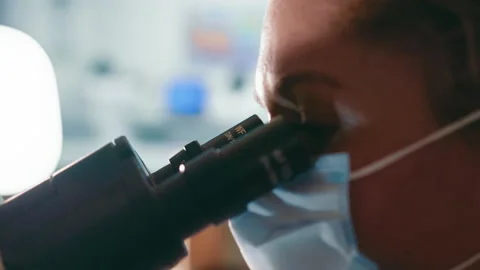 Close-up of the eyes of a researcher looking into a microscope. Research in the Stock Footage 234302926