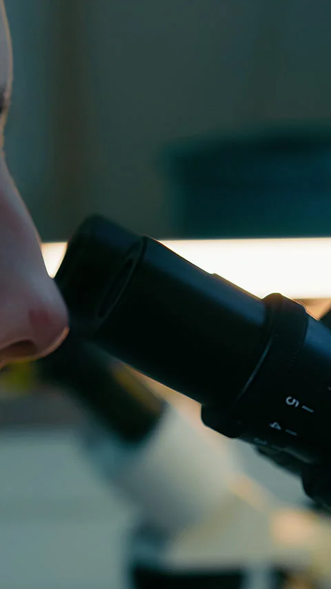 Close-up of the eyes of a researcher looking into a microscope. Research in the Stock Footage 340191737