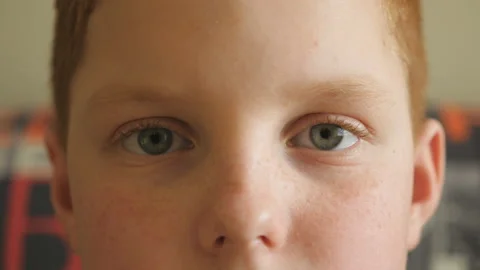Close up eyes of small red-haired boy blinking and looking with a tired sight Stock Footage 140606677