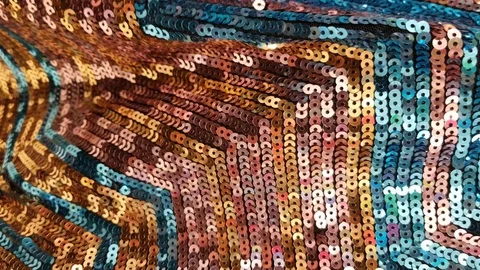 Close up of a fabric decorated with shiny gold, brown and blue sequins Stock Footage 125901339