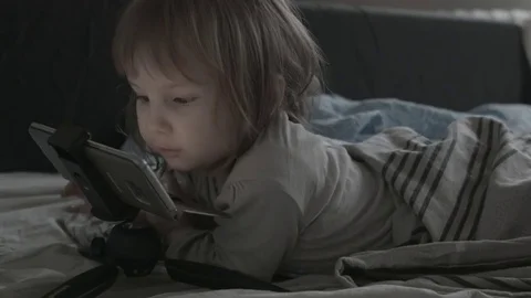 Close up of face and hands of 2 years old kid playing computer games lying in Stock Footage 85213222