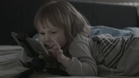 Close up of face and hands of 2 years old kid playing computer games lying in Stock Footage 85213395