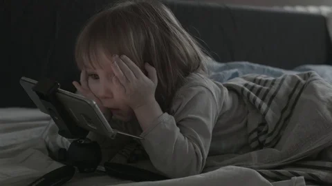 Close up of face and hands of 2 years old kid playing computer games lying in Stock Footage 85213775