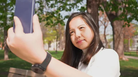 Close up face of Asian black straight hair woman sitting on a chair at a park Stock-Footage 169856629
