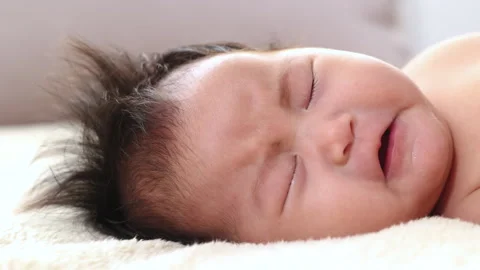 Close-up the face of asian newborn baby lying on beige bed looking camera a.. Stock Footage 249491253