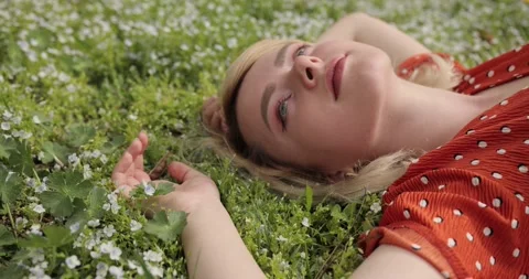 Close-up of the face of an attractive young blonde woman lying on the flowers of Stock Footage 154678543
