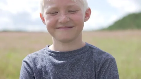 Close-up of the face of a beautiful blonde boy in the summer in the field of Stock Footage 134768677