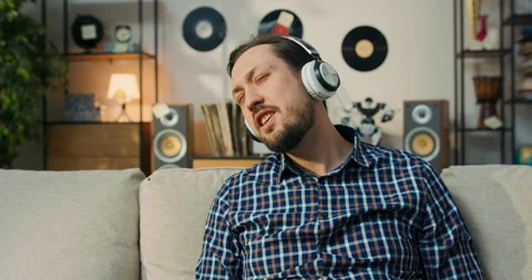 Close-up of the face of a boy with bearded dark hair listening to music on 스톡 동영상 200836307