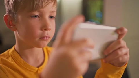 Close up face of a boy with smartphone, at home. Caucasian child spending tim Stock Footage 135916981
