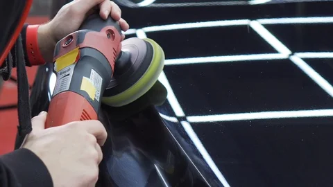 Close-up of face of car wash worker, he carefully polishes a black expensive car Stock Footage 115932378