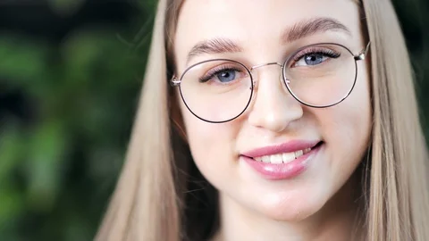 Close-up face of charming positive young European woman wearing glasses looking Vídeos de archivo 107364080