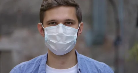 Close-up face of cheerful young man take off medical mask and smiling looking at Stock Footage 164667998