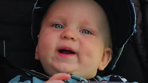 Close-up of the face of a cute full-cheeked baby sitting in a stroller Video stock 307680992