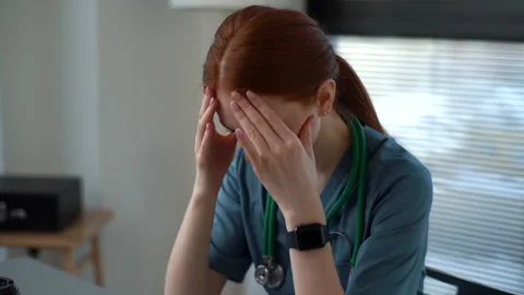 Close-up face of exhausted tired young female doctor in blue green medical Stock Footage 152996296