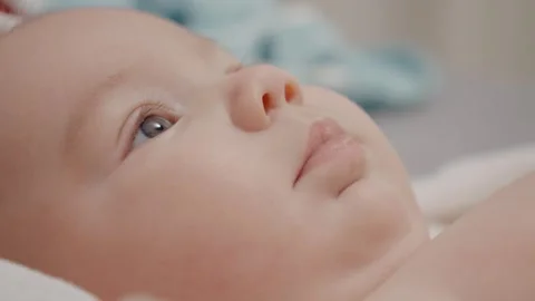 Close up face features of a baby playing alone while lying on the bed. Stock Footage 302451975