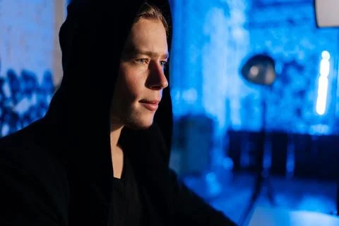 Close-up face of handsome wanted hacker man in sweatshirt with hood engaged in Foto stock
