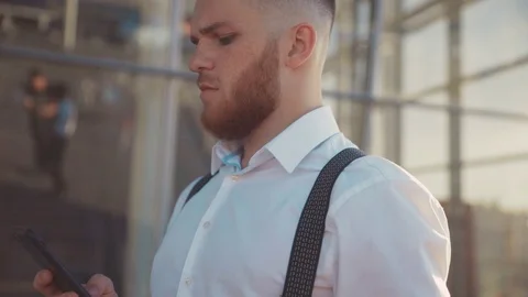 Close up face handsome young man uses phone looks around walking down street Stock Footage 115668610