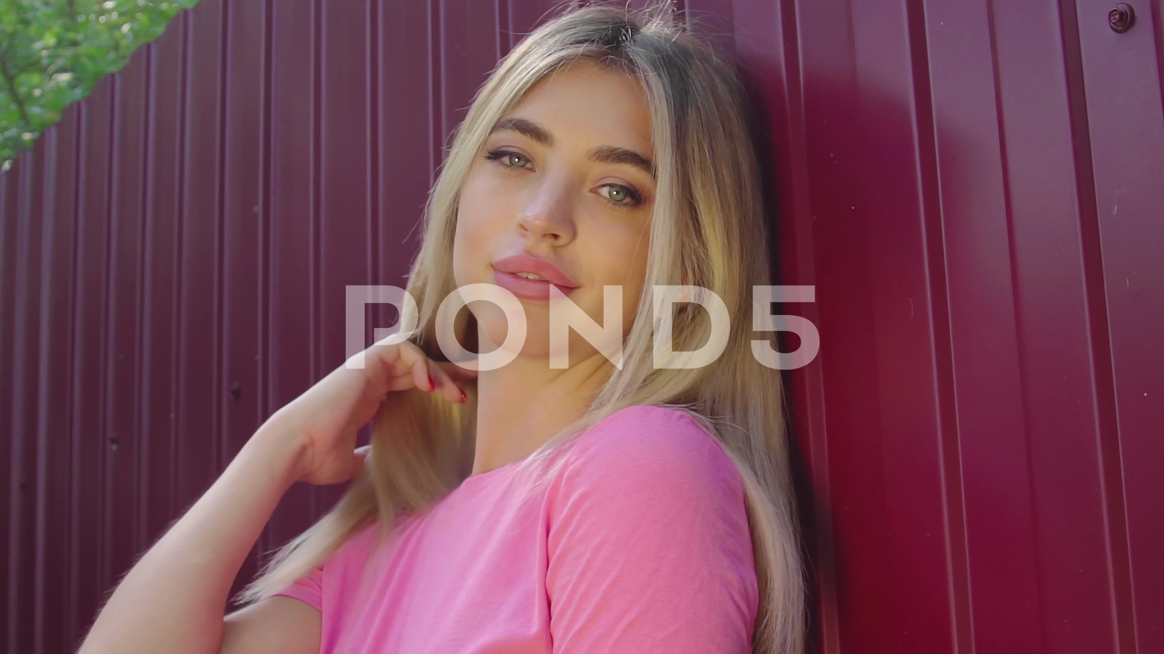 Close up face hot blonde woman in pink tank top posing by dark red iron fence photo