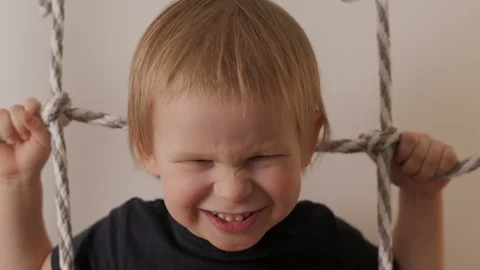Close up face of laughing cute little boy posing on rope ladder having fun and Stock Footage 125437192