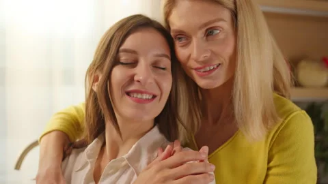 Close up face lesbian couple hugging in kitchen at home near window. LGBT Stock Footage 268474775