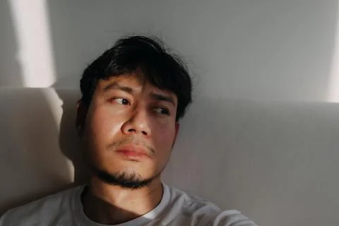 Close up face of lonely man feeling depressed and bored in low light room. Stockfoto's
