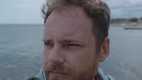 Close-up of the face of a man with a beard against the background of the sea Stock Footage 115480323
