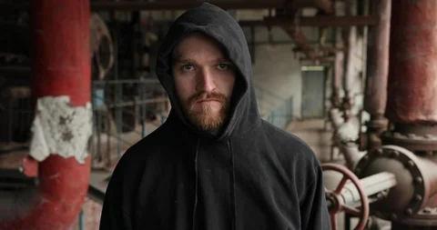 Close up the face of a man with a beard in a black hood stands on in an Stock Footage 126383089