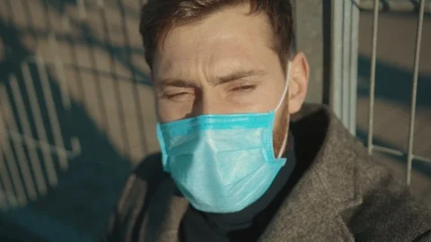 Close up face man wearing Protective Face Mask sitting near fence border sick Stock Footage 126617650