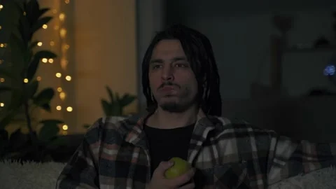 Close-up of the face of a man who bites off an apple and watches a movie 库存影片 170423249