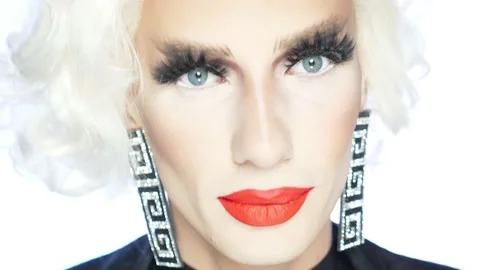Close-up face of parody actor blonde with red lips, blue eyes and catchy makeup Stock Footage 166837871