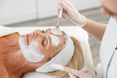 Close up face peeling mask, spa beauty treatment, skincare. Senior woman getting Stock Photos
