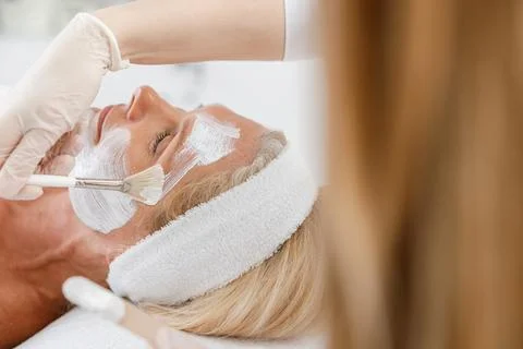 Close up face peeling mask, spa beauty treatment, skincare. Senior woman getting Stock Photos