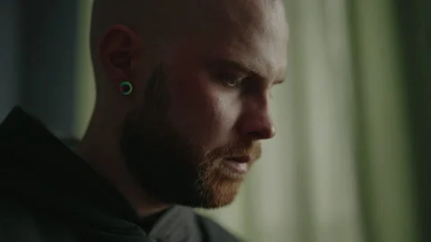 Close-up face of pensive bald man with ginger beard and ear piercing expressing Stock Footage 305515603